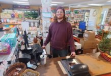 smiling man stands at the cash register in the checkout lane
