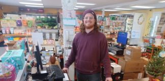 smiling man stands at the cash register in the checkout lane