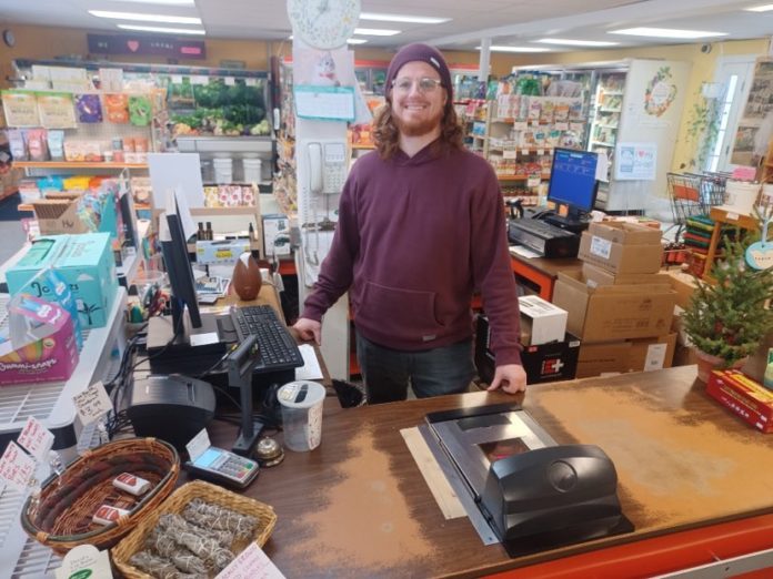 smiling man stands at the cash register in the checkout lane