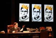 A woman sits at a desk, wearing the robes of a judge