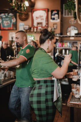 Two bartenders pour drinks