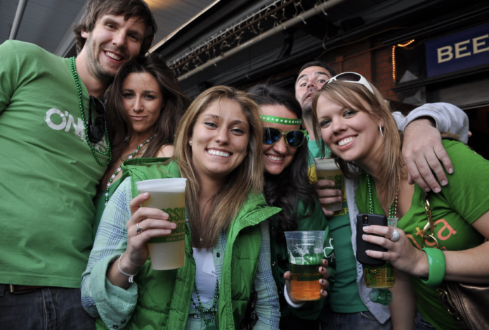 Friends hold up their beer and smile