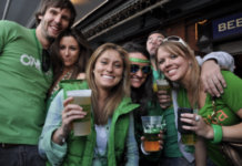 Friends hold up their beer and smile