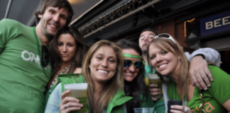 Friends hold up their beer and smile