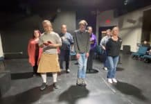 actors rehearse on a black stage