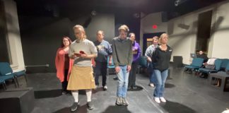 actors rehearse on a black stage