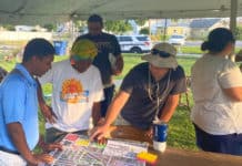 three people stand around a table, looking at a map