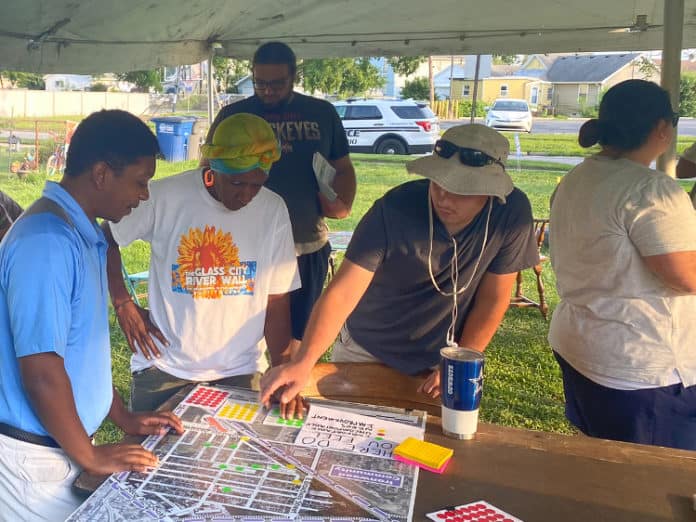 three people stand around a table, looking at a map