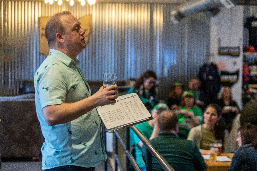 a man holding a pint addresses the crowd at a brewery