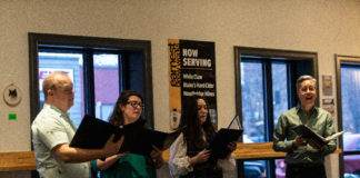 singers perform at Earnest Brew Works while holding portfolios of music