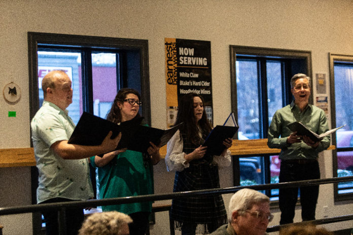 singers perform at Earnest Brew Works while holding portfolios of music