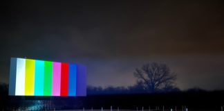 outdoor movie screen displays color bars against a dark sky