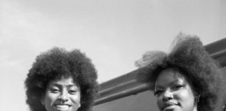 two young women stand in front of a tent at an outdoor festival