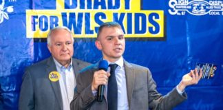 young man wearing a jacket and tie holds a microphone