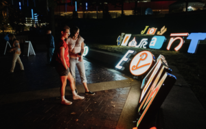 Two people look at neon letters.