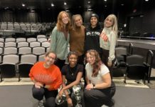 Seven women pose together on stage