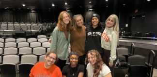 Seven women pose together on stage