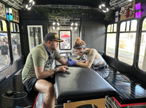 Brick House Bus owner Jordyn Tinney performing a tattoo on the bus.
