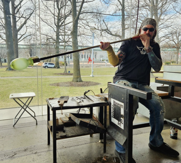 an artist works on a glass blown piece