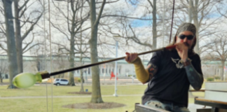 an artist works on a glass blown piece