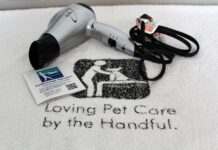 PetMassage Aquatics Hydrotherapy Video A white towel with the company's name and logo under a silver blow dryer and business card.