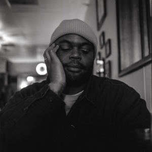 A person with his hand against his head and eyes closed. 