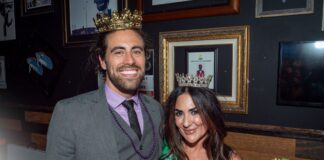 Two winners, (left) man and (right) woman smiling with their crowns on.