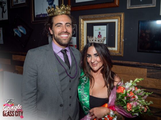 Two winners, (left) man and (right) woman smiling with their crowns on.