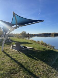 Two lawn-like chairs under umbrellas facing the Maumee River.