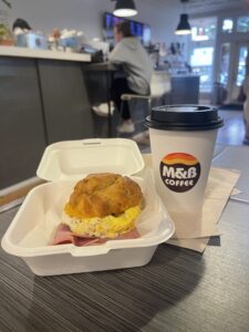 A hot coffee and ham, egg and cheese biscuit pictured inside Maddie & Bella Coffee Roasters